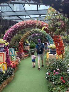 Un père et sa fille marchent main dans la main à travers un décor floral féerique à Floral Fantasy, dans Gardens by the Bay à Singapour.