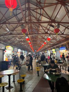 Intérieur animé du Maxwell Food Court à Singapour, avec ses lanternes rouges suspendues et ses étals de street food asiatique.