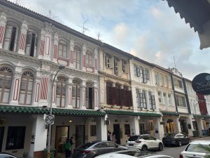 Façades colorées de shophouses traditionnelles à Singapour, mêlant architecture coloniale et influences asiatiques dans une rue animée.